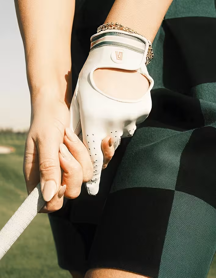 Hand wearing a white golf glove gripping a golf club