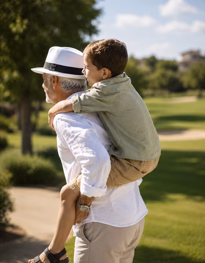 Grandfather giving his grandson a piggyback ride on a golf course