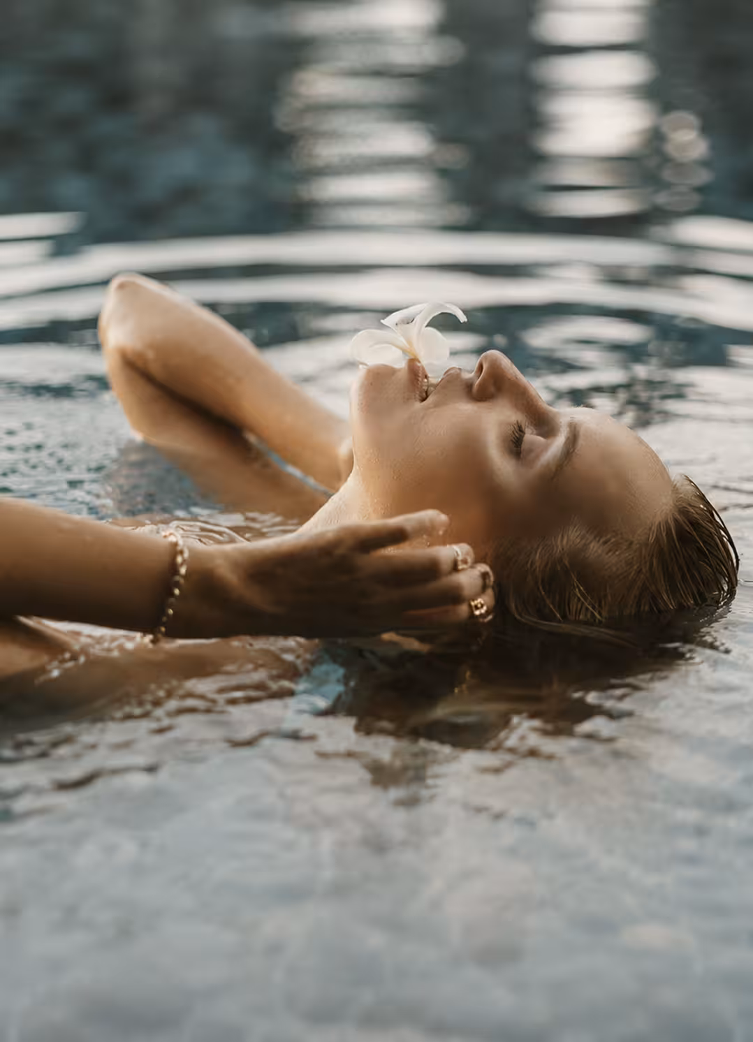 Woman floating peacefully in water with a white flower