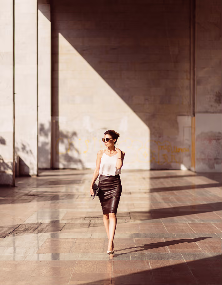 Woman walking through a sunlit minimalist architectural space with tall stone columns