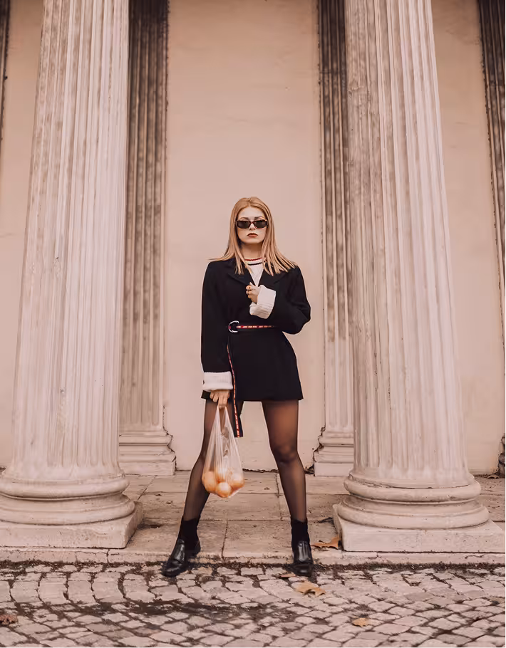 Woman standing between classical stone columns in an urban setting