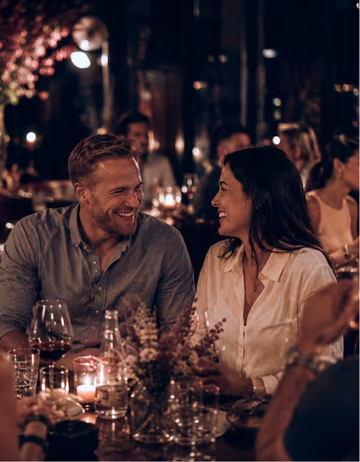 Couple dining at a candlelit outdoor table at night